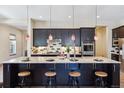 Gorgeous kitchen boasts black cabinetry, pendant lighting, granite counters, and a spacious island with seating for four at 24322 E Mineral Dr, Aurora, CO 80016