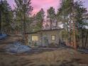 Cozy home surrounded by lush greenery, complemented by a welcoming patio area with seating for outdoor relaxation at 28251 Meadow Rue Rd, Evergreen, CO 80439