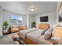 Bright bedroom featuring a large bed, sitting area by the window, and a mounted TV at 8236 E 137Th Dr, Thornton, CO 80602