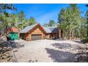 Log home with attached garage and a separate storage shed in a wooded area at 17940 Smugglers Rd, Monument, CO 80132