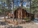 Beautiful log home with brick chimney encircled by rustic wood fence at 17940 Smugglers Rd, Monument, CO 80132