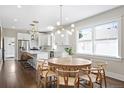 Open dining area with a round wooden table, modern chandelier, and seamlessly connected to the kitchen space at 1534 Meade St, Denver, CO 80204