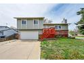 Charming two-story home with an attached garage, red stairs, and well-maintained yard at 8595 Field Ct, Arvada, CO 80005