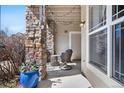 Cozy patio with stone pillar, string lights, seating, and a view of lush greenery at 9390 W Chatfield Pl # 108, Littleton, CO 80128