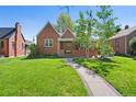 Beautiful brick home with a lush green lawn, a stone pathway, and mature trees at 1434 Clermont St, Denver, CO 80220