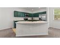 Modern kitchen with green cabinets, stainless steel appliances, and island sink at 10578 E Jewell Ave, Aurora, CO 80012