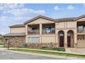 Close up of a townhome with stone accents, covered balcony, arched entry, and multiple garages at 7131 S Wenatchee Way # F, Aurora, CO 80016