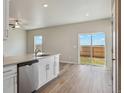 Open kitchen area with white cabinets, a dishwasher, and sliding glass doors leading to the backyard at 48245 Shetland Dr, Bennett, CO 80102