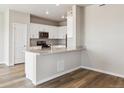 Modern kitchen featuring white cabinets, stainless steel appliances, a breakfast bar, and wood-look floors at 48245 Shetland Dr, Bennett, CO 80102