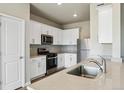 Bright kitchen with stainless steel appliances, white cabinets and light countertop breakfast bar at 48245 Shetland Dr, Bennett, CO 80102