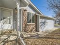 Home exterior featuring brick accents, white door, and well-maintained landscaping at 19 Shetland Ct, Highlands Ranch, CO 80130