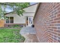 Inviting front entrance with stone steps leading to a bright doorway and brick accent wall at 4483 S Eagle Cir, Aurora, CO 80015