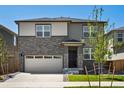 Charming two-story home with a stone facade, attached two-car garage and a neatly kept lawn at 6068 Hourglass Dr, Brighton, CO 80601