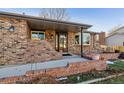 Close up of the brick home's entrance with a covered porch and bay window at 13215 Peacock Dr, Lone Tree, CO 80124