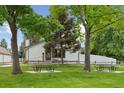 Charming home exterior with a lovely yard, mature trees, picnic tables, and a white picket fence at 8867 Yukon St # 49, Broomfield, CO 80021