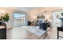 Bright living room boasts a sliding glass door to the patio, neutral colors and wood-look flooring at 10211 Ura Ln # 1-308, Thornton, CO 80260