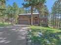 Inviting home boasts a two-car garage, covered entry, and is nestled amidst a lush, green lawn and mature trees at 4228 Scenic Village Dr, Evergreen, CO 80439