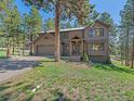 Two-story home featuring a well-manicured lawn and a welcoming covered front entry in a wooded, landscaped setting at 4228 Scenic Village Dr, Evergreen, CO 80439