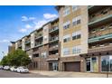 Multi-story condo building with balconies, brick accents, garage access, and street parking at 1441 Central St # 203, Denver, CO 80211
