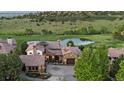 Aerial view of a stone home by a pond and golf course showcasing the lush surroundings and serene environment at 7208 Raphael Ln, Littleton, CO 80125
