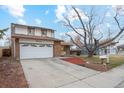 Charming two-story home with a well-manicured front yard and a large driveway leading to an attached garage at 9777 W 75Th Way, Arvada, CO 80005