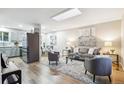 Bright living room features hardwood floors, a skylight, and flows into a dining area with modern furnishings at 9777 W 75Th Way, Arvada, CO 80005