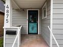 A welcoming front porch featuring a unique teal door with ironwork and fresh gray siding at 4875 Lowell Blvd, Denver, CO 80221