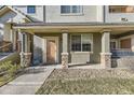 Inviting front porch featuring stone pillars, a glass storm door and manicured landscaping in front of the property at 22520 E Ontario Dr # 101, Aurora, CO 80016