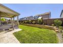 Lush backyard with a well-maintained lawn, retaining wall, and covered patio at 14437 Grape St, Thornton, CO 80602