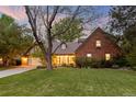 Charming brick home featuring mature trees, a well-manicured lawn, and warm lighting enhancing its inviting curb appeal at 6248 S Coventry Ln, Littleton, CO 80123