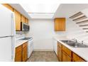 Bright kitchen with skylight, white appliances, wood cabinets, and staircase at 4896 S Dudley St # 8-11, Littleton, CO 80123