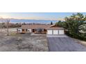 Ranch-style home with three-car garage, landscaped front yard, and mountain views at 10353 N Chatfield Dr, Littleton, CO 80125