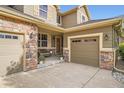 Inviting entrance with a cozy bench, stone accents, and a well-maintained three-car garage at 15056 Fillmore Way, Thornton, CO 80602