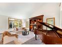 Bright living room with fireplace, piano, large windows, and comfortable seating at 2595 S Harlan Ct, Lakewood, CO 80227