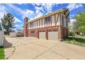View of a two car garage, greenhouse, and brick and Tudor design at 12341 E Cedar Cir, Aurora, CO 80012