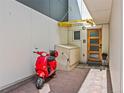 Stylish front entrance with a modern wood door, brick walkway, and a vibrant red scooter parked nearby at 3133 Blake St # 3, Denver, CO 80205