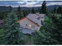 Aerial view of a home with a spacious deck, surrounded by lush green trees and beautiful mountain scenery at 96 Carolyn Rd, Evergreen, CO 80439