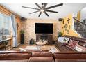 Spacious living room with a stone accent wall, leather furniture, and a large TV at 7097 S Patsburg Way, Aurora, CO 80016