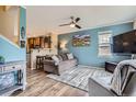 Comfortable living room featuring wood floors, modern ceiling fan and blue accent wall open to kitchen at 24748 E Layton Pl, Aurora, CO 80016