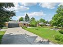 Inviting home featuring a green lawn, mature trees, a two-car garage, and lovely neighborhood views at 721 Park Ln, Lakewood, CO 80214