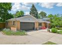 Exterior view of charming brick home, green lawn, mature trees, and attached garage at 721 Park Ln, Lakewood, CO 80214