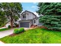 Inviting two-story home with a well-kept lawn, mature trees, and a brick-accented front entrance at 10172 Woodrose Ln, Highlands Ranch, CO 80129