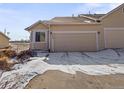 Exterior view of a townhome with an attached garage and snowy landscaping in a suburban neighborhood at 12292 E 2Nd Dr, Aurora, CO 80011