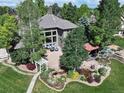 An aerial view of a beautiful home with mature trees, landscaping, gazebo, and a lovely backyard water feature at 6940 Saddleback Ave, Firestone, CO 80504