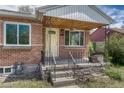 Close-up of the inviting brick porch and yellow front door with iron railings and stone accents at 1334 Xavier St, Denver, CO 80204