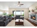 Open living room with fireplace, hardwood floors, ceiling fan, and outside view at 15779 W 83Rd Pl, Arvada, CO 80007