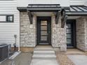 Inviting modern townhome entrance with stone accents, gray trim, dark blue front door, and address number above the door at 2042 S Holly St # 3, Denver, CO 80222