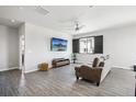 Bright living room with modern ceiling fan, stylish gray floors, and an entertainment center with a large screen TV at 1702 Metcalf Dr, Erie, CO 80516