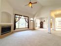 Bright living room showcasing a fireplace, vaulted ceilings, large windows, and plush carpet at 3231 E 102Nd Pl, Thornton, CO 80229