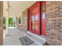 View of brick front porch with a red front door and matching storm door at 3653 E 133Rd Ct, Thornton, CO 80241